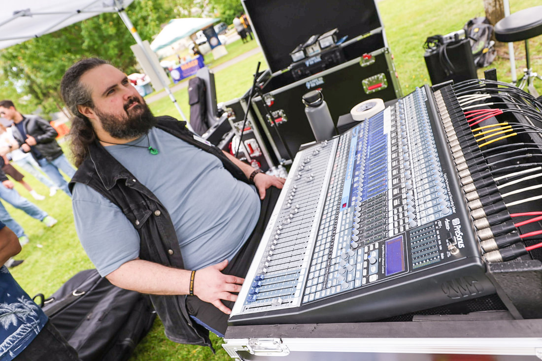 Mike Jauregui operating a professional digital mixing console at an outdoor event